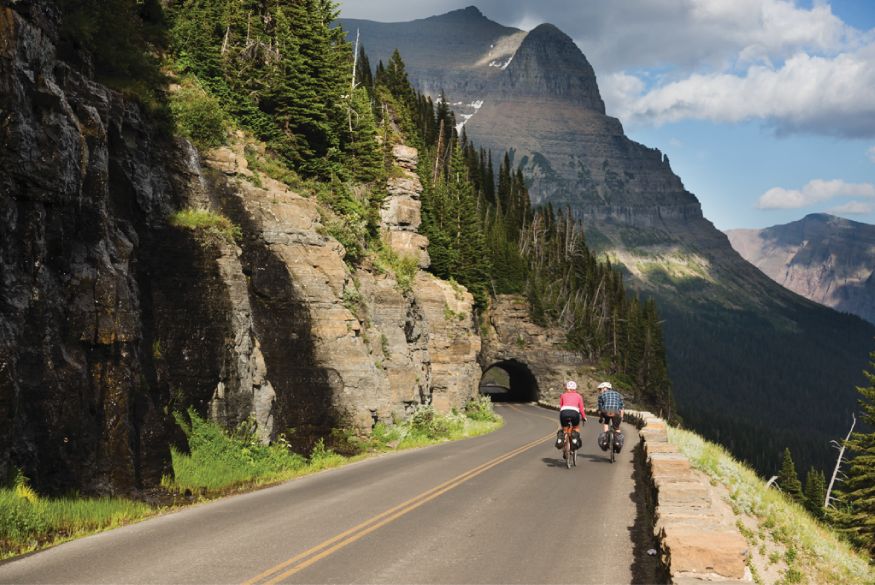 Two people on bikes riding down a mountain road 